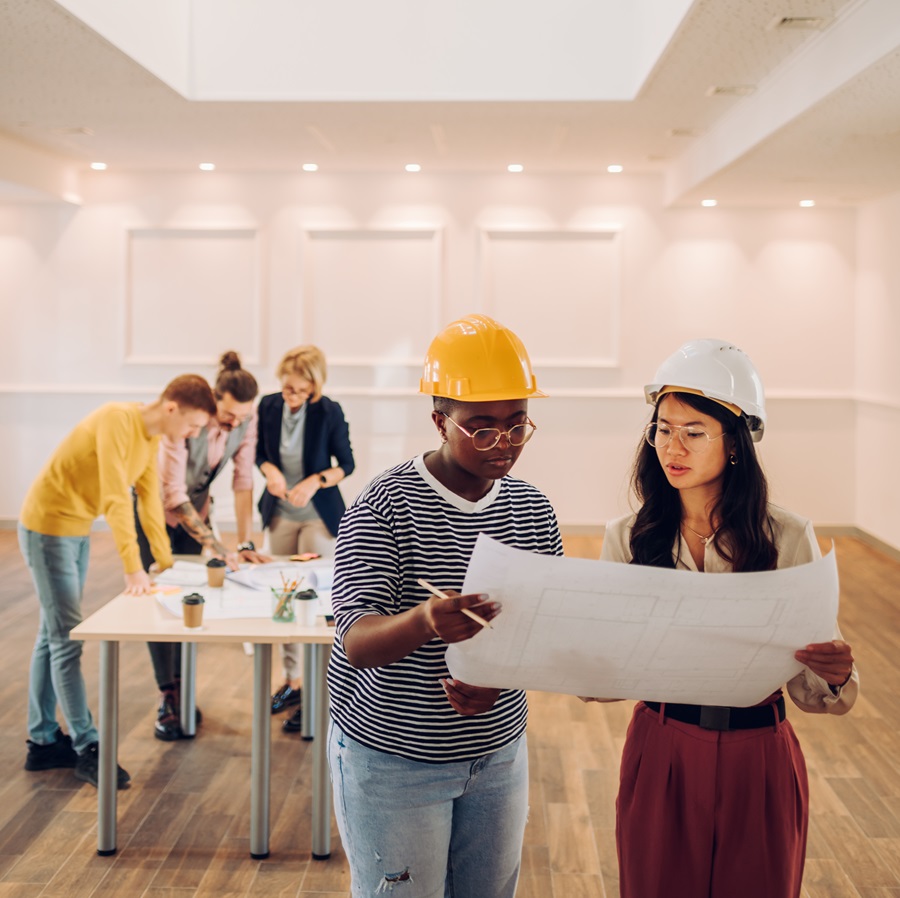 Portrait of two multiracial architect looking at blueprints in an office